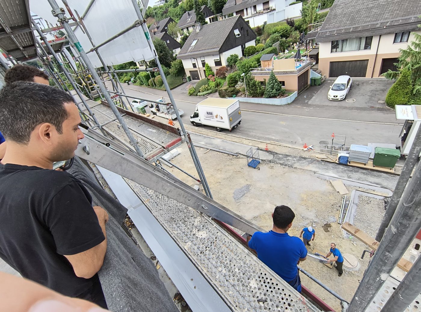 Blick von der Liftplattform auf Lastwagen und Baustelle, zwei Personen am Lift